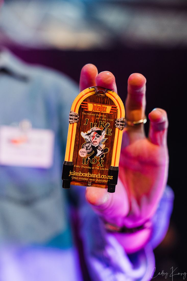 A hand holding up a miniature jukebox with the band lit in purple behind