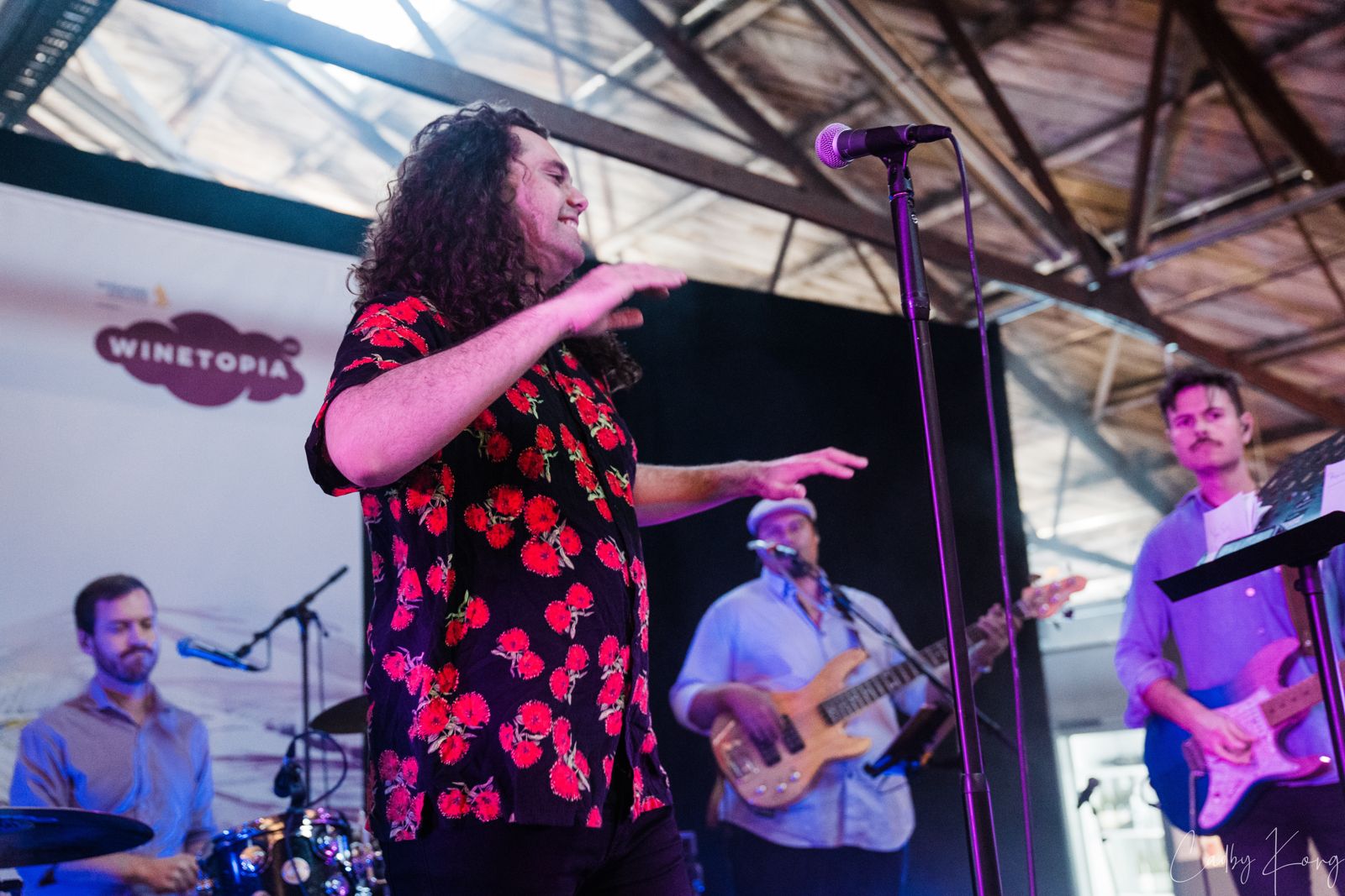 Lead singer in a floral shirt mid song with the band behind